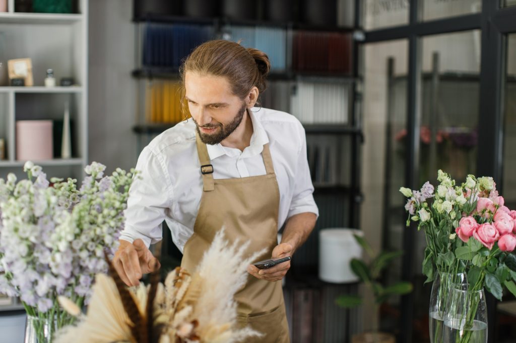 Male florist in flower shop. Floral design studio, making decorations and arrangements.
